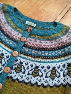 a knitted sweater with buttons on the front and back, sitting on a wooden floor