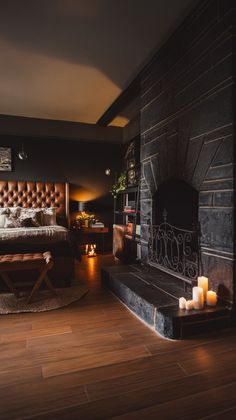 a bedroom with wood floors and a fireplace in the corner, surrounded by lit candles