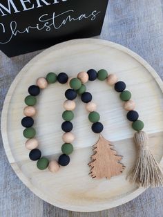 a wooden beaded necklace with a christmas tree on it and a card next to it