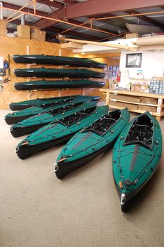 several canoes are lined up on the floor in front of a wall with shelves