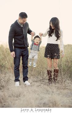 a man, woman and baby are standing in the middle of a field with tall grass