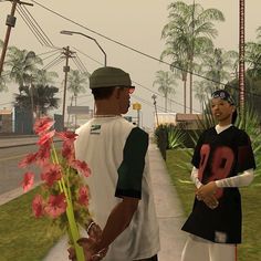 two men standing next to each other on a street with flowers in front of them