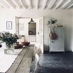 the dining room table is set with white chairs and flowers in vases on it