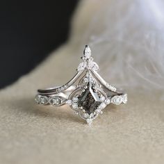 a close up of a diamond ring on a white furnishing surface with feathers in the background