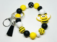 a yellow and black beaded bracelet with a bee keychain on it's side