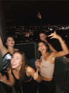 four girls are posing for the camera in front of a cityscape at night