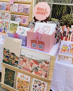 many cards are on display at an outdoor market stall, including boxes with designs for sale