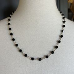 a black and silver necklace on a mannequin