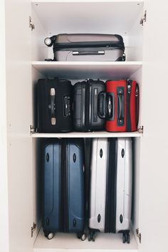 several suitcases are lined up on the shelves in a closet, all different colors and sizes