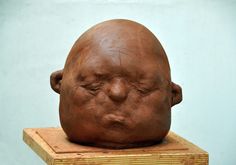 a sculpture of a man's head on top of a wooden block