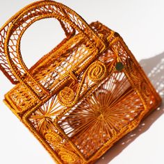 an orange rattan purse sitting on top of a white table next to a shadow