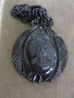 Vintage circa 1930 black celluloid cameo necklace. This vintage 2.5'' black gothic necklace features a large celluloid cameo on a 22'' celluloid link chain. The chain has a hook closure that closes in the front. This estate find is large and wonderful. It wears with a bold style. The cameo has beautiful features and it is beautifully framed on it's carved backdrop. Lovely vintage condition. Victorian Black Medallion Jewelry, Black Victorian Medallion Jewelry, Black Cameo Medallion Jewelry, Vintage Black Cameo Jewelry, Vintage Black Cameo Necklace, Vintage Black Carved Jewelry, Vintage Black Medallion Jewelry, Vintage Black Medallion Necklace, Black Cameo Necklace In Vintage Style