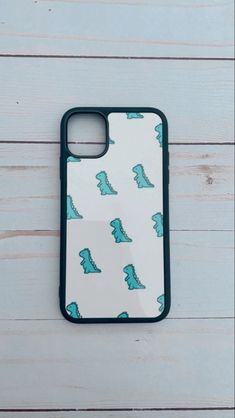 a phone case with dinosaurs on it sitting on a wooden table next to a white wall