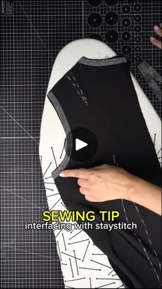 someone is sewing on a black and white piece of fabric with scissors in it,