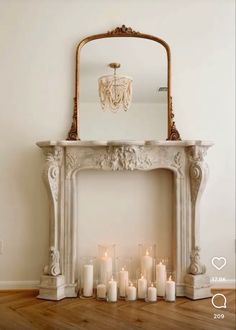 a white fireplace with candles in front of it and a mirror on the wall behind it