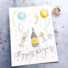 a birthday card with balloons, champagne and confetti on the table next to it