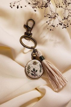 a keychain with a tassel hanging from it's side on a white fabric