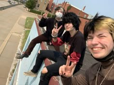 four young men posing for the camera with their fingers in the air and wearing face masks