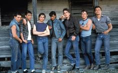 a group of young men standing next to each other in front of a wooden building