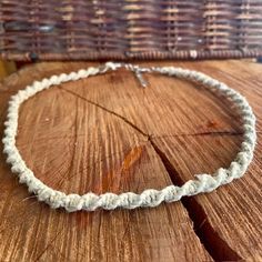 a white rope necklace sitting on top of a wooden table next to a wicker basket