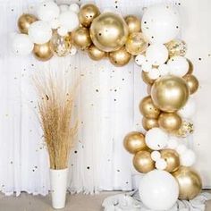 a bunch of white and gold balloons hanging from a wall next to a vase filled with dry grass