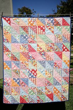 a colorful quilt hanging from a clothesline on a clothes line in front of a house