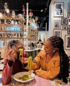 two women sitting at a table eating spaghetti