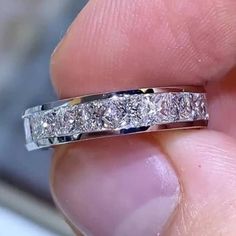 a person is holding a wedding ring in their left hand and it has three diamonds on the side