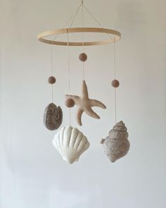 a mobile with seashells and starfish hanging from it's sides on a white wall