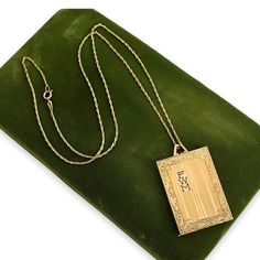 "Description: Beautiful antique Art Deco style gold filled locket that features pinstriping and a monogram of FWM on the front. This is a rather large rectangular locket that has a swirled leafy frame etched all around the vertical striped etched lines on the front. There is a rectangular cartouche on the top left side that has the letters FWM monogramed inside it in a bold font. This locket was designed to hold three photos - one on each side and one in the middle frame holder with an oval open Gold Rectangular Jewelry Keepsake, Gold Rectangular Keepsake Jewelry, Gold Rectangular Keepsake Necklace, Gold Rectangular Necklace For Keepsakes, Gold Rectangular Locket Necklace Gift, Gold Rectangular Locket Necklace For Gifting, Gold Rectangular Locket Necklace For Gift, Vintage Engraved Rectangular Pendant Necklace, Art Deco Yellow Gold Locket Necklace