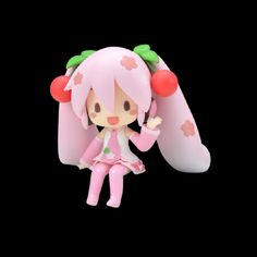 a pink and green figurine sitting on top of a black surface