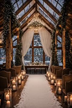 an indoor wedding venue with candles and chandeliers in the middle of the aisle