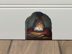 a mouse reading a book on top of a wooden floor next to a white door