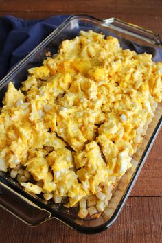 a casserole dish with eggs and onions in it on a wooden table top