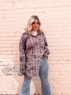 a woman standing in front of a brick wall with her hands on her hips and looking at the camera