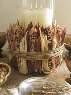 an arrangement of corn on the cob with a lit candle and other food items