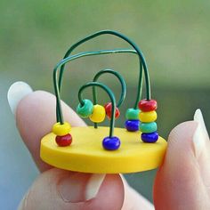 a small yellow object with colorful beads on it's side in someones hand