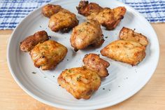 a white plate topped with chicken wings on top of a wooden table