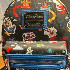 Disneyland Play At The Parks Carry Around Happy Memories Of Your Disney Trips With This Mini Backpack From Loungefly. The Simulated Leather Design Has A Colorful Allover Pattern Featuring Your Favorite Attractions, Characters, And Snacks. It Will Get You Excited About Your Next Visit To The Happiest Place On Earth! Simulated Leather Grain Mini Backpack Double Zipper Main Compartment Loungefly Logo Metal Pulls Silvertone Hardware Adjustable Padded Shoulder Straps Top Carry Handle Side Slip Pocket Black Disney Bag For Theme Park, Black Disney Backpack For Travel, Black Disney-style Bag For Theme Park, Black Disney Style Bag For Theme Park, Themed Black Backpack For Theme Parks, Black Backpack For Theme Parks, Black Backpack For Theme Park, Black Backpack With Zipper For Disney Fan Events, Lion King Pride Rock