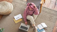 a woman sitting on the floor with her laptop and notebooks in front of her