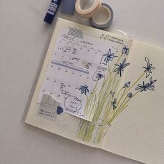 an open notebook with blue flowers and tape on it, next to some other items