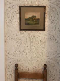 a wooden bench sitting in front of a wall with a painting hanging on it's side