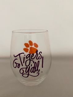 a wine glass with the words tigers go girl painted on it and an orange paw