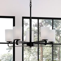 a chandelier with four lights hanging from it's sides in front of a window