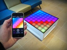 a person holding up a smart phone in front of a table with an electronic sound board on it