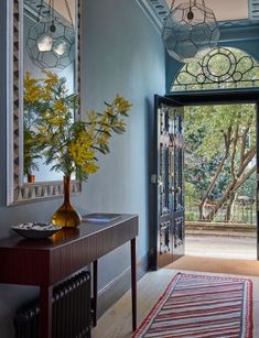 a hallway with blue walls and wooden flooring has a large mirror on the wall