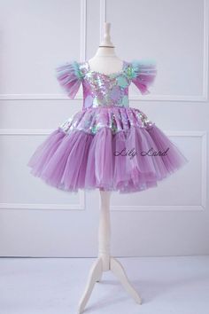 Make your little girl's birthday extra special with this gorgeous  Mermaid Dress! This stunning toddler birthday outfit features a beautiful mermaid-inspired design with a flowing lilac tutu skirt and a mermaid detail. The dress is perfect for any special occasion, including birthdays, cake smashes, and princess-themed parties. Made with high-quality materials, this baby girl tutu dress is soft, comfortable, and breathable, ensuring that your little one stays cozy and stylish all day long. Wheth Fitted Mermaid Tutu Dress For Birthday, Purple Fitted Fairy Dress For Birthday, Whimsical Purple Princess Dress With Ruffles, Birthday Princess Fairy Dress With Ruffles, Mermaid Tulle Princess Dress For Birthday, Birthday Princess Mermaid Dress In Tulle, Princess Fairy Dress With Ruffles For Birthday, Princess Style Fairy Dress With Ruffles For Birthday, Whimsical Purple Tutu Dress With Ruffles