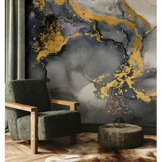 a chair and ottoman in front of a wall with gold paint splattered on it