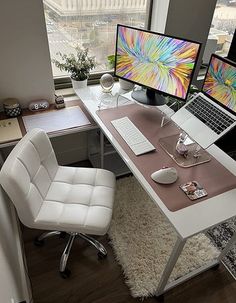 a desk with two computer monitors and a laptop on it, in front of a window