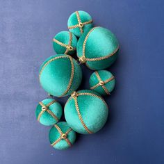 several green balls with gold string tied around them sitting on a blue surface, top view